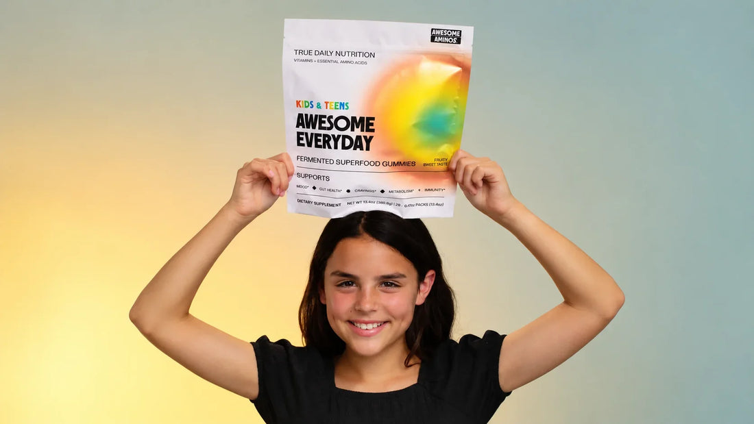 Smiling child holding an Awesome Everyday™ Kids & Teens gummy pouch.