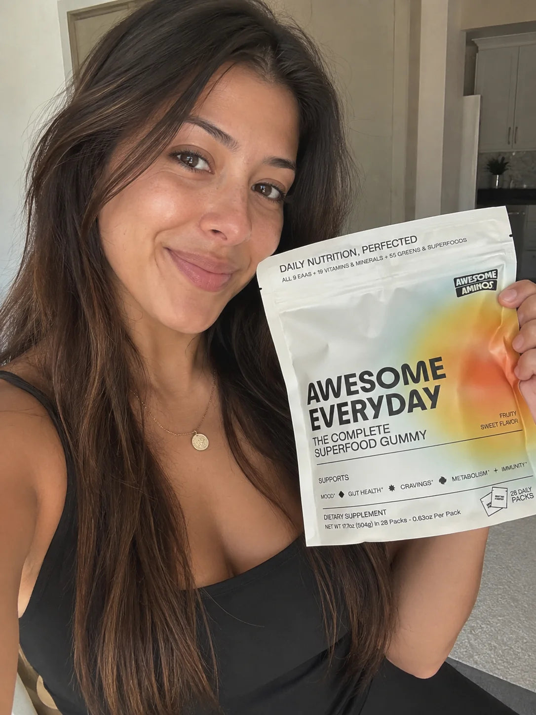 A woman holding up a pack of Awesome Everyday gummies