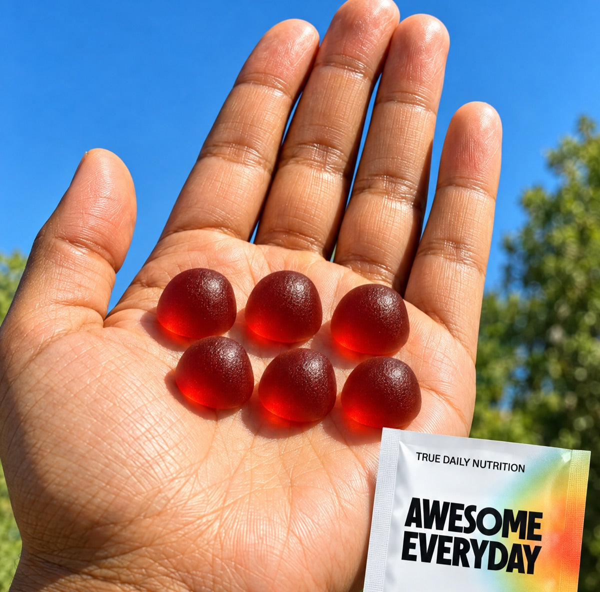 Awesome Everyday gummies in an open palm, next to a daily pack